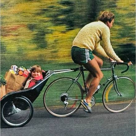 A cyclist towing a loaded trailer along a country road.