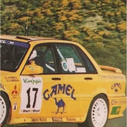 A rally car in period livery on a forest stage.
